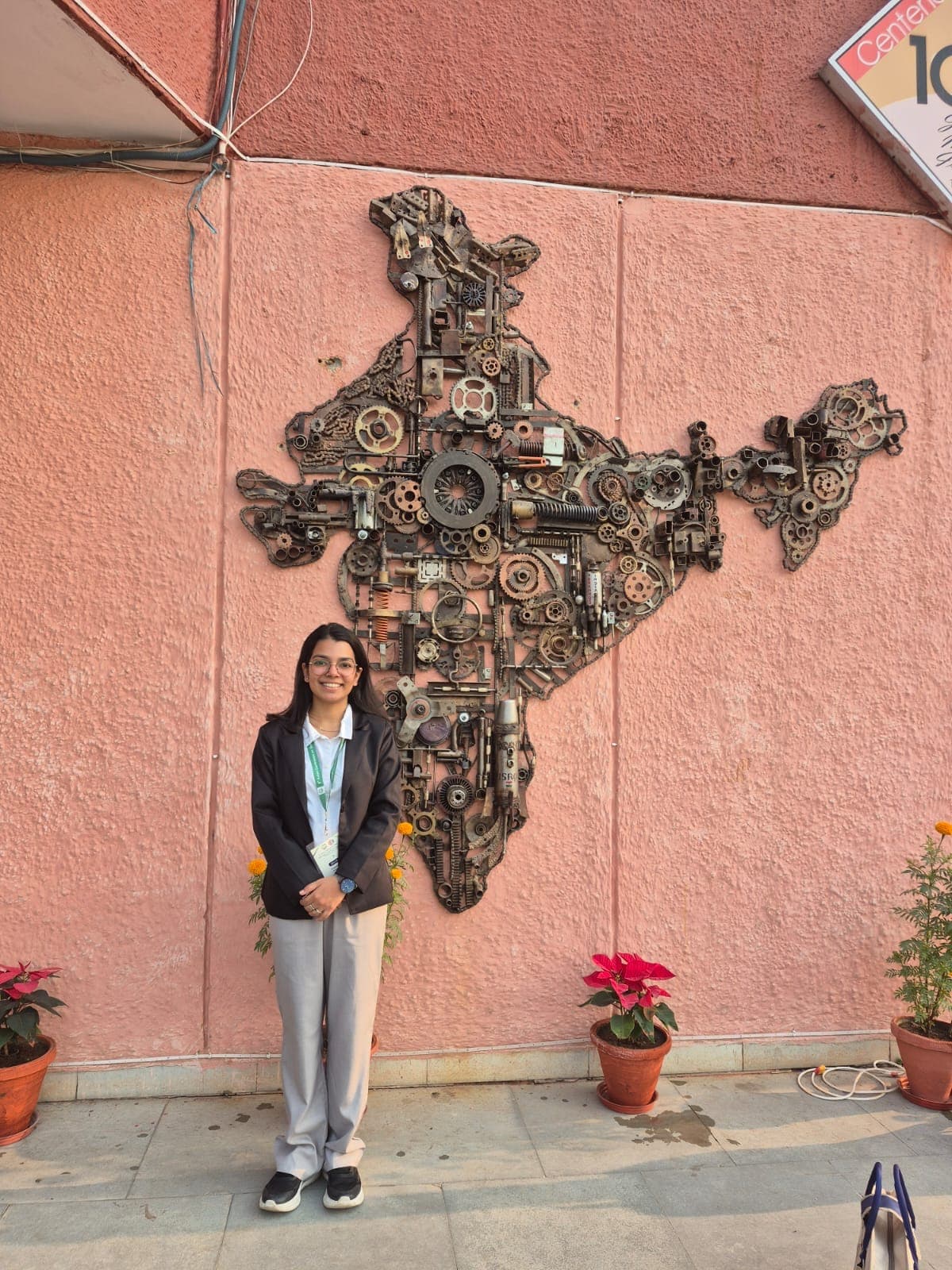 Jannat Khosla, geospatial researcher, standing in front of a metal-art map of India